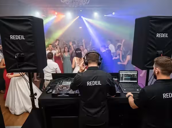 DJ en consola cerca de la mesa de los novios durante la fiesta