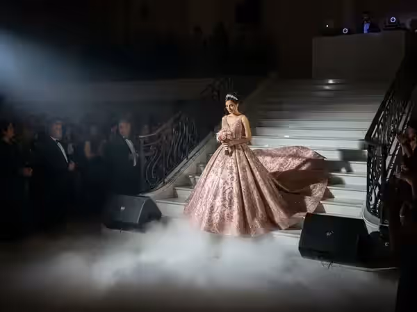 Entrada de la quinceañera por la escalera con humo bajo y seguidor de luz