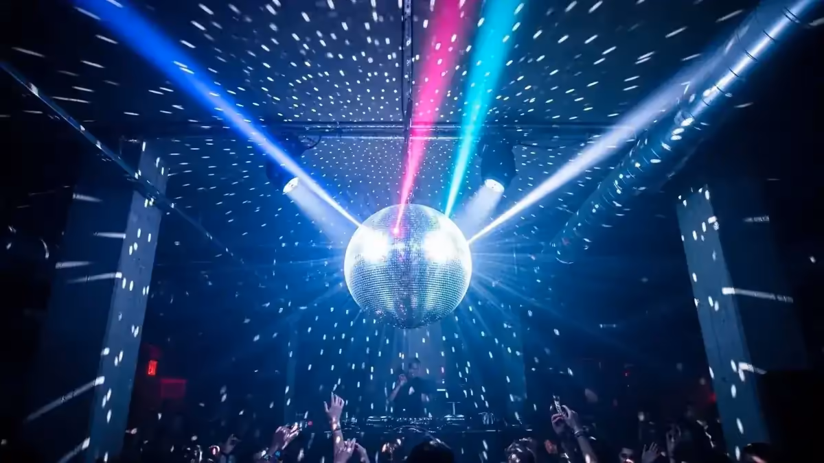 Bola disco de espejos con DJ y luces de colores en fiesta retro