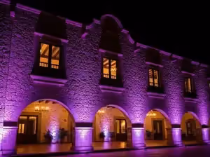 Iluminación arquitectónica de fachada colonial con luces moradas - Hacienda eventos CDMX