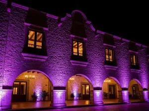 Iluminación arquitectónica de fachada colonial con luces moradas - Hacienda eventos CDMX