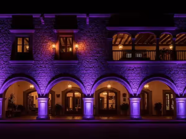 Arcos de piedra y balcón de hacienda en morado durante un evento nocturno