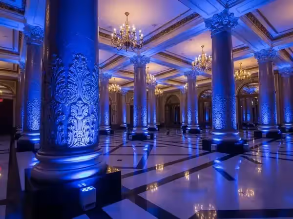 Salón de gala con columnas bañadas en azul y piso de mármol