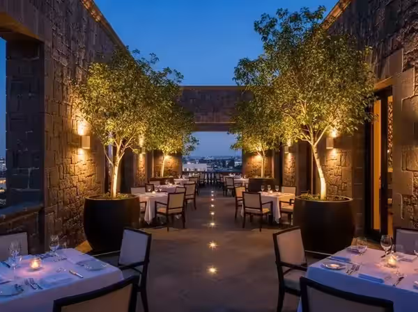 Árboles y muro de piedra iluminados en la terraza de un restaurante