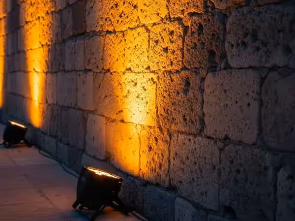 Par LED proyectando luz ámbar sobre muro de cantera en un evento